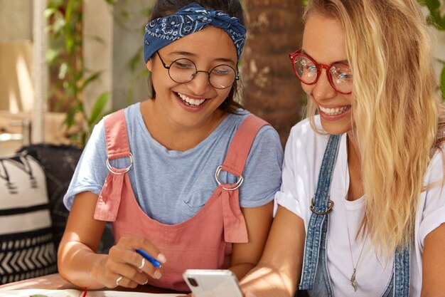 Weiblichkeit, Technologiekonzept. Positive interracial lächelnde Frauen arbeiten zusammen, um Fremdsprache zu lernen