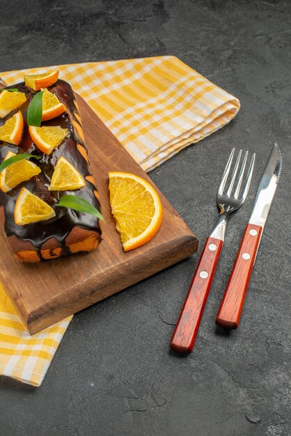 Weiche Kuchen an Bord und Zitronen mit Blättern auf grünem Handtuch des dunklen Tischmaterials schneiden