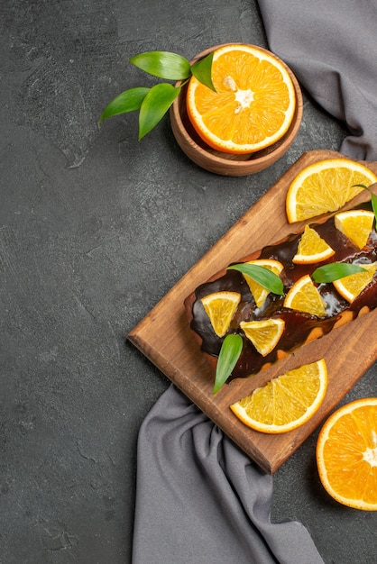 Weiche leckere kuchen schneiden zitronen mit keksen auf holzschneidebrett und handtuch auf dunklem tisch