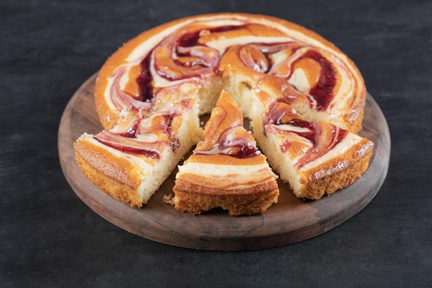 Weiche leckere Torte mit gemischten Zutaten auf Holzbrett.