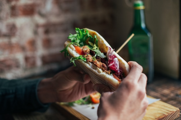 Weichzeichneraufnahme des Mannes, der köstliches großes Frühstück im kühlen Restaurant oder im Café hat, setzt Guacamole oder Avocado auf Roggenbrot-Toast