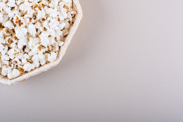 Weidenkorb mit gesalzenem Popcorn für den Filmabend auf weißem Hintergrund. Foto in hoher Qualität