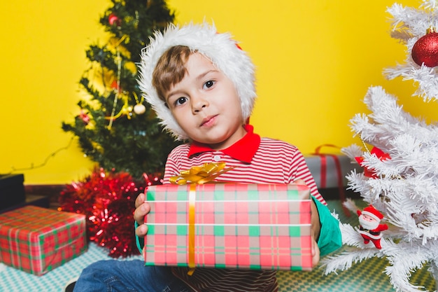 Kostenloses Foto weihnachten concepto mit dem kind, das präsentkarton hält