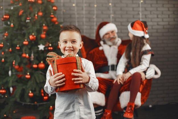 Weihnachten, Kinder und Geschenke. Der Weihnachtsmann brachte Kindern Geschenke. Freudige Kinder mit Geschenken, die den Weihnachtsmann umarmen.