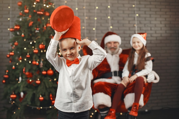 Weihnachten, Kinder und Geschenke. Der Weihnachtsmann brachte Kindern Geschenke. Freudige Kinder mit Geschenken, die den Weihnachtsmann umarmen.