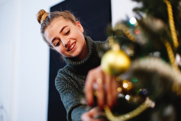 Weihnachten und Neujahr Vibes. Bezaubernde junge Frau in einer Strickjacke wird fertig