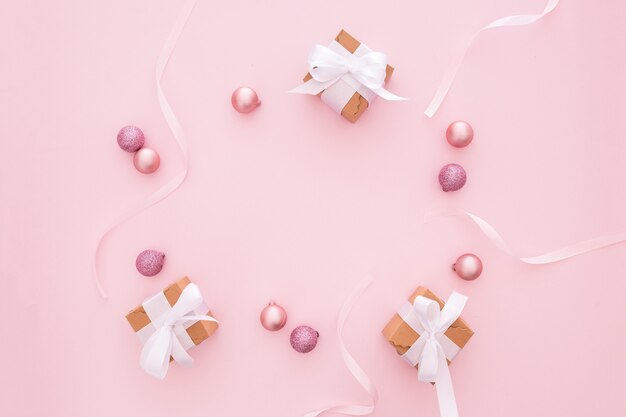 Weihnachtsbälle und -geschenke auf einem rosa Hintergrund