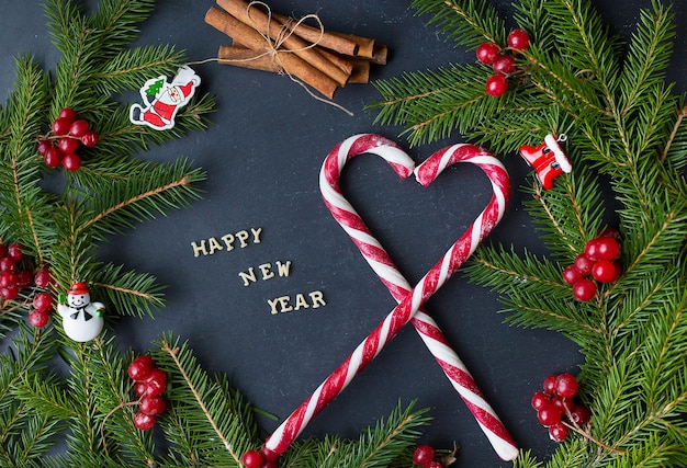 Weihnachtsbaum mit ornamenten und süßigkeiten auf schwarzem hintergrund. die aufschrift frohes neues jahr.
