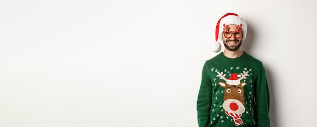 Kostenloses Foto weihnachtsferien feierkonzept glücklicher mann mit weihnachtsmütze und lustigen partygläsern, die wieder stehen