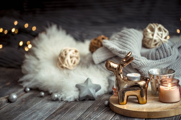 Weihnachtsfestwand mit Spielzeughirsch, verschwommene Wand mit goldenen Lichtern und Kerzen, festliche Wand auf Holzdeck Tisch