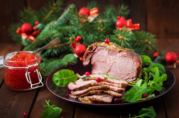 Weihnachtsgebackener Schinken und roter Kaviar, serviert auf dem alten Holztisch.