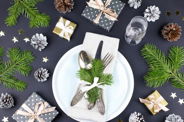 Weihnachtsgedeck mit tafelsilber geschenkbox und dekorationen in schwarz- und goldfarben