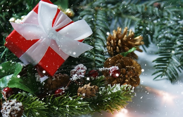 Weihnachtsgeschenk eingebettet in Dekorationen mit Schneeüberlagerung