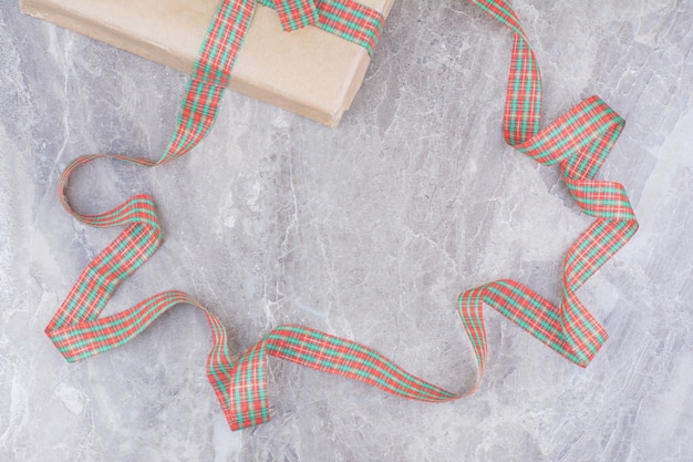 Kostenloses Foto weihnachtsgeschenk mit festlichem bogen auf marmorhintergrund.