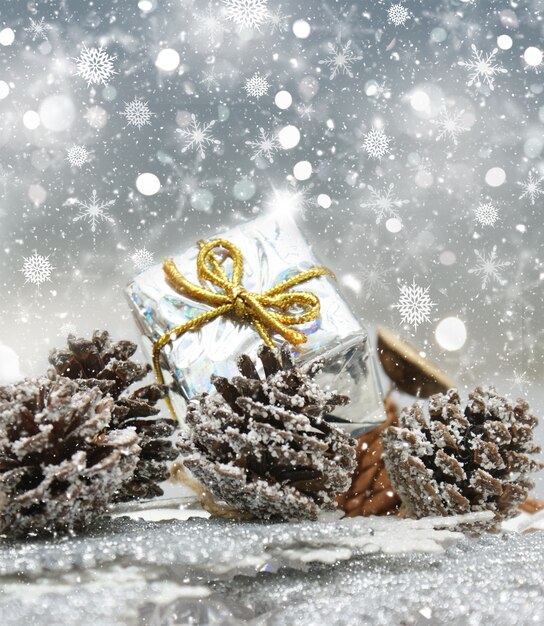 Weihnachtsgeschenk und Tannenzapfen auf Schneeflocke Hintergrund