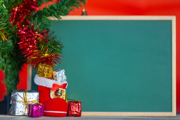 Weihnachtsgeschenkboxen in verschiedenen Farben platziert vor der grünen Tafel