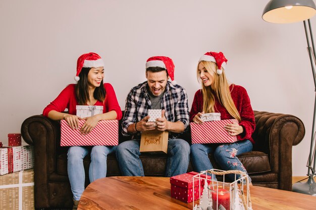 Weihnachtsgeschenkkonzept mit drei Freunden auf Couch