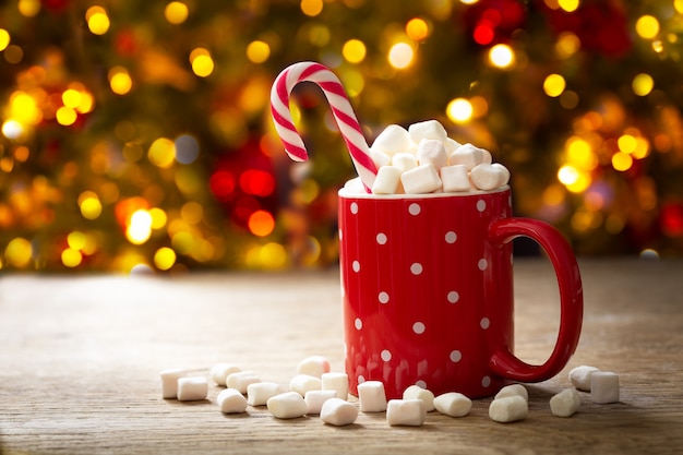 Weihnachtsgetränk. tasse heiße schokolade mit marshmallows und roter zuckerstange auf festlichem hintergrund