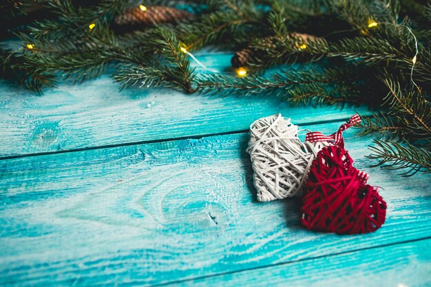 Weihnachtsherzen auf einem blauen Holztisch mit Weihnachtsbaum. Attrappe, Lehrmodell, Simulation.