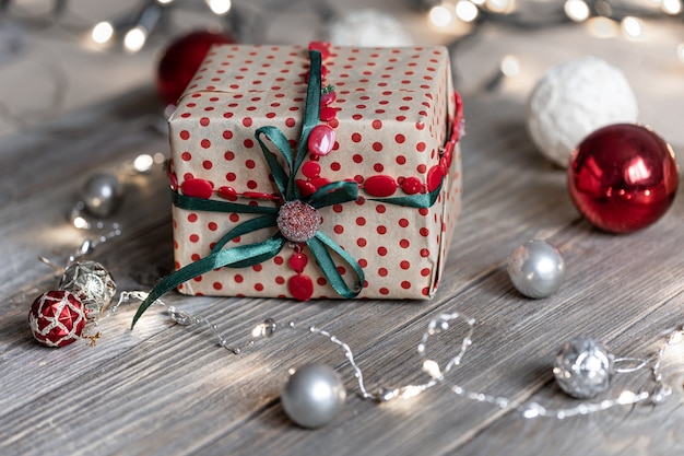 Weihnachtshintergrund mit Geschenkbox, Bällen auf dem Baum und Bokeh-Lichtern.