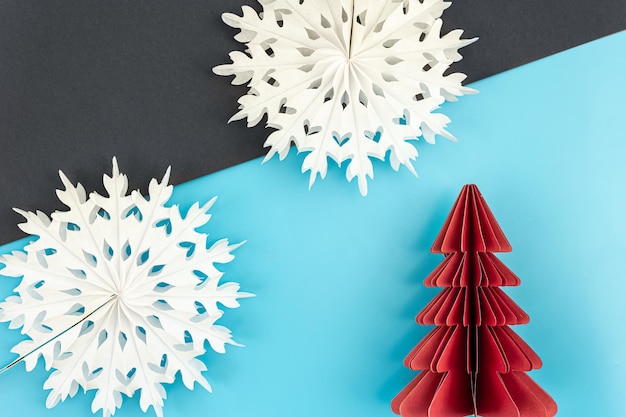 Weihnachtshintergrund mit origami-papierbaum und schneeflocken flach gelegt