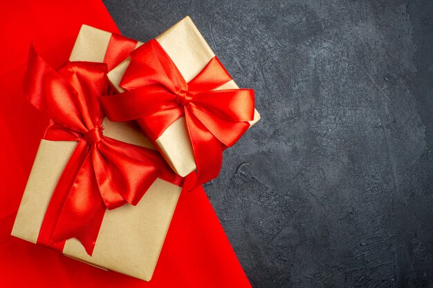 Weihnachtshintergrund mit schönen Geschenken mit bogenförmigem Band auf einem roten Handtuch auf einem dunklen Hintergrund