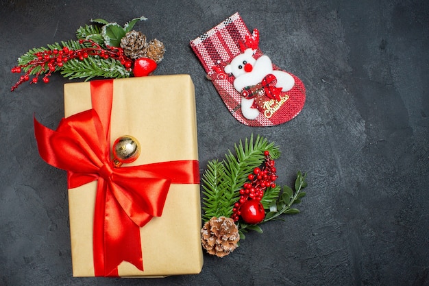 Weihnachtshintergrund mit schönen Geschenken mit bogenförmigem Band und Tannenzweigdekorationszubehörweihnachtssocke auf einem dunklen Tisch v