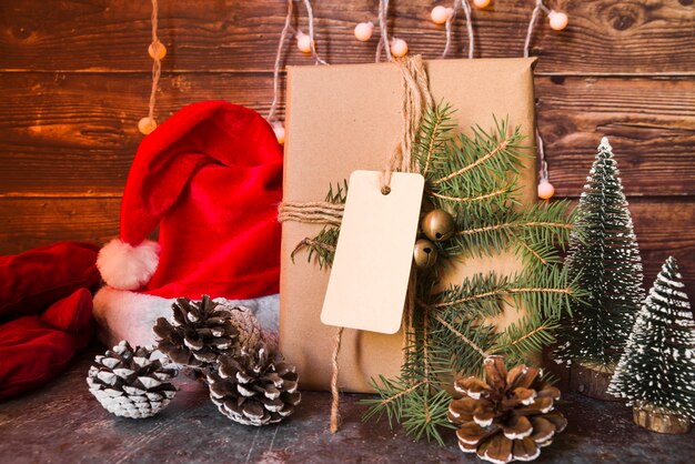 Weihnachtshut nahe Geschenkbox verzierte den Tannenzweig mit Aufkleber