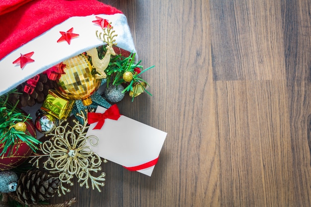 Weihnachtskarte und Weihnachtsmütze mit Dekorationen auf Holz backgrou