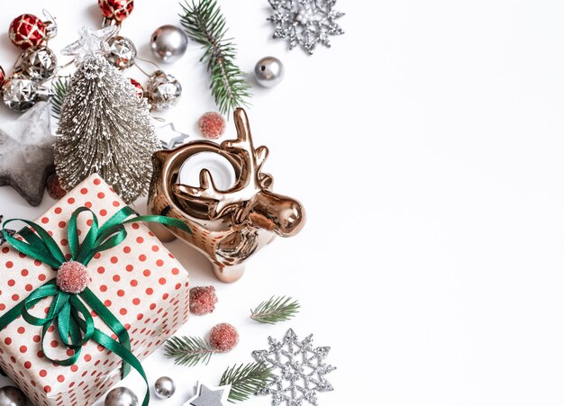 Weihnachtskomposition. Geschenke, Tannenzweige, rote Verzierungen an weißer Wand. Winter, Neujahrskonzept. Flach gelegt, isometrisch, Platz für Text