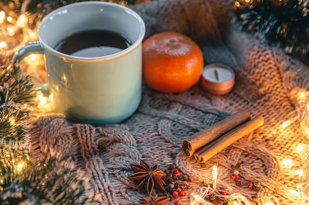 Weihnachtskomposition mit einer Tasse Teegewürzen auf einem gestrickten Element