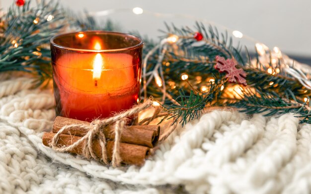 Weihnachtskomposition mit Kerze und Zimtstangen auf verschwommenem Hintergrund