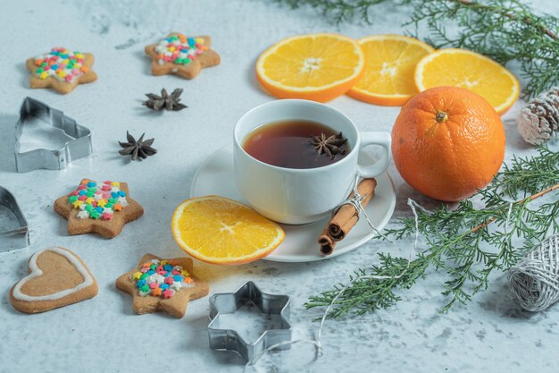 Weihnachtskonzept. Frischer Tee mit Orange und Keksen.