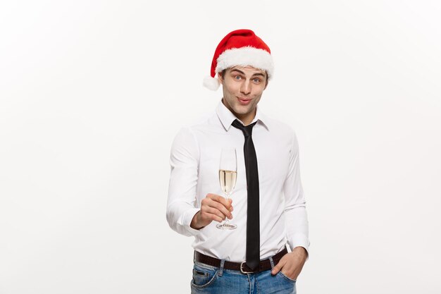 Weihnachtskonzept Gutaussehender Geschäftsmann feiert frohe Weihnachten und ein gutes neues Jahr und trägt eine Weihnachtsmütze mit einem Glas Champagner