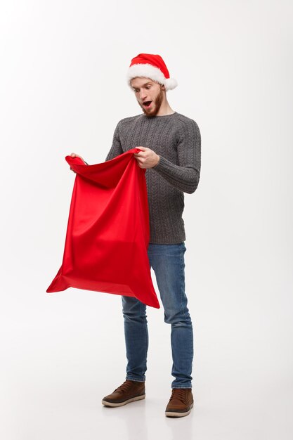 Weihnachtskonzept Junger Bart, gutaussehender Mann, aufregende offene Weihnachtsmann-Big-Bag für Geschenke