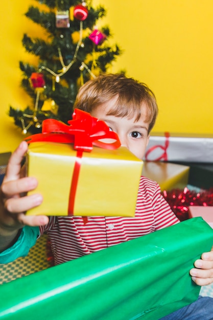 Weihnachtskonzept mit dem Jungen, der Präsentkarton hält