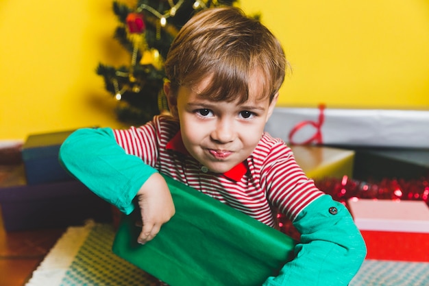 Kostenloses Foto weihnachtskonzept mit dem kind, das grüne geschenkbox hält