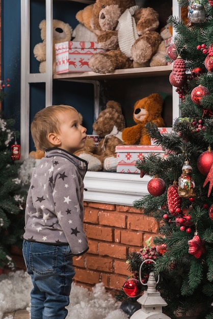 Kostenloses Foto weihnachtskonzept mit dem kind, das weihnachtsbaum betrachtet