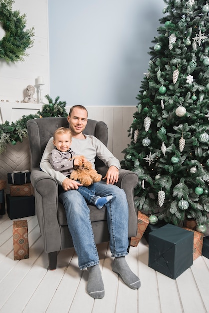 Kostenloses Foto weihnachtskonzept mit dem vater, der sohn auf couch hält