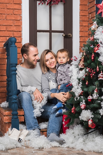 Kostenloses Foto weihnachtskonzept mit der jungen familie, die draußen sitzt