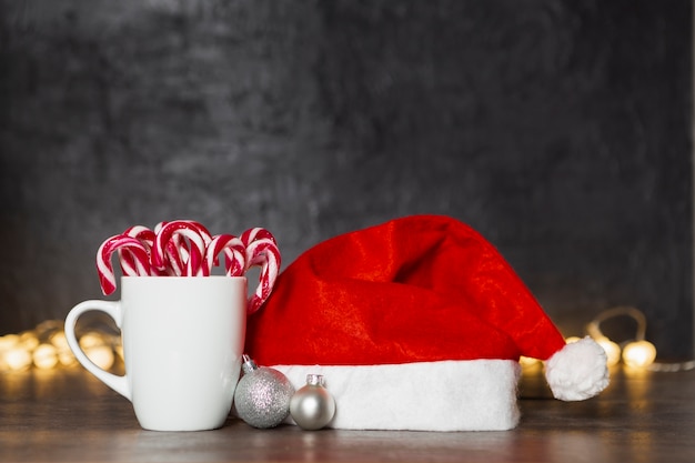 Weihnachtskonzept mit Sankt Hut und Becher mit Süßigkeit