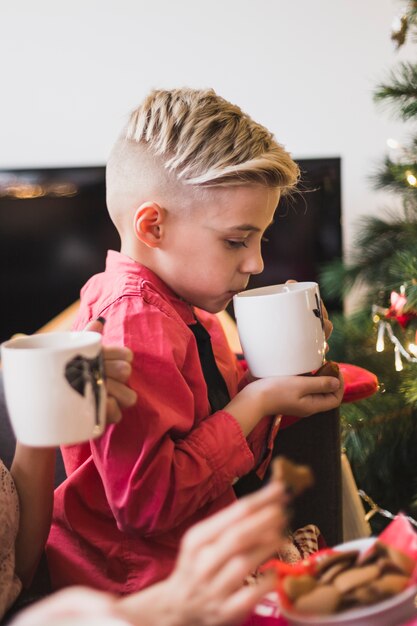 Weihnachtskonzept mit trinkendem Tee des Jungen