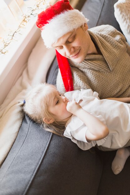 Weihnachtskonzept mit Vater und Tochter auf der Couch