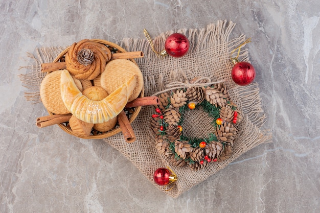 Weihnachtskranz, baumschmuck und ein backkorb auf marmor.