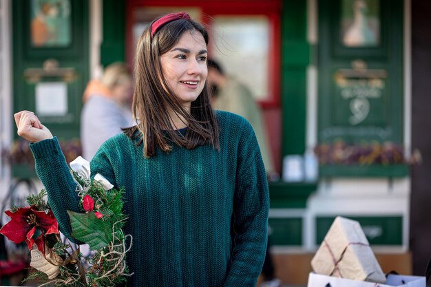 Weihnachtskranz in den Händen eines stilvollen Frauenstadtspaziergangs