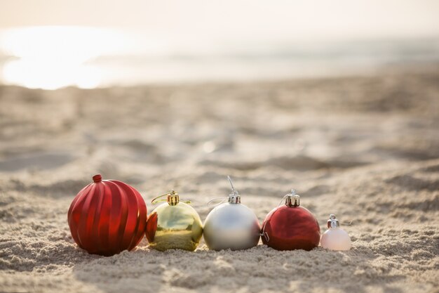 Weihnachtskugeln auf dem Sand angeordnet