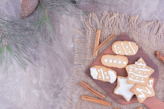 Weihnachtslebkuchen in Oval- und Sternform auf einem Holzbrett mit Zimtstangen herum