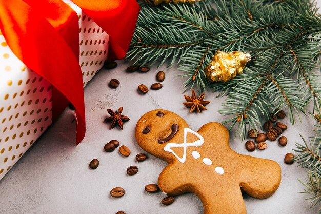 Weihnachtslebkuchen, Kaffeebohnen, Tannenzweig und Präsentkarton auf grauem Boden