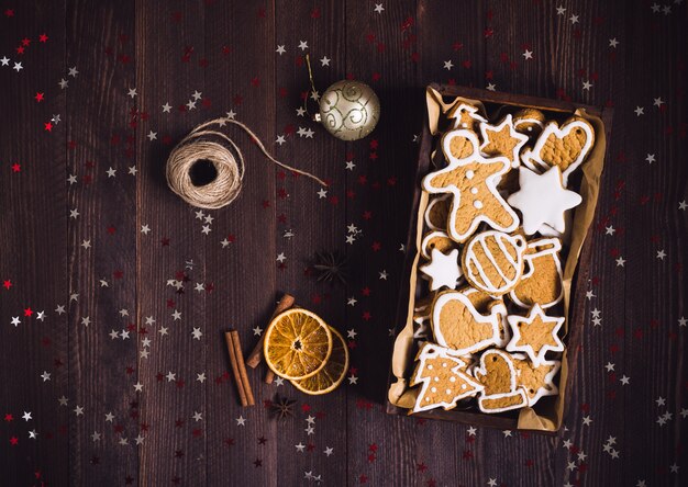 Weihnachtslebkuchenplätzchen im dunklen Foto der Draufsicht des festlichen Gebäcks des Holzkistegeschenks