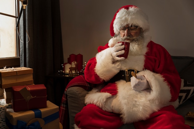 Kostenloses Foto weihnachtsmann, der einen tasse kaffee trinkt